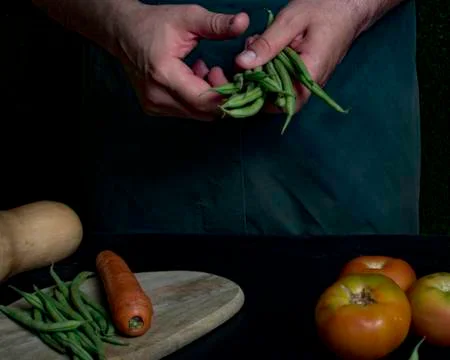 Man with green apron presenting vegetables and garden vegetables. Stock Photos
