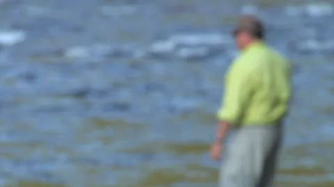 Man in Green Comes Into Focus As He Fishes Stock Footage 24704774