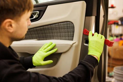 A man in green gloves cleans inside car door in automotive design Stock Photos