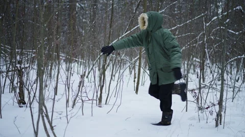 A man in a green jacket walks through the winter forest Stock Footage 295422659