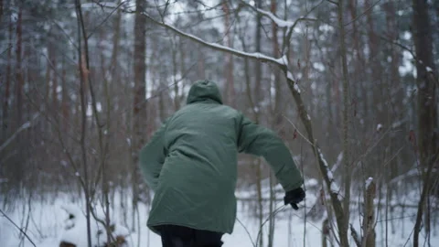 A man in a green jacket walks through the winter forest Stock Footage 295422783