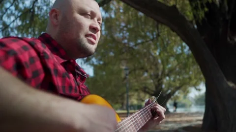 A man with a green mohawk playing guitar and singing at park Stock-Footage 139274089