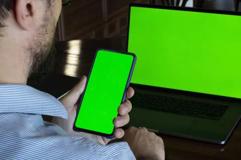 Man with green screen in front of green laptop screen Stock Photos