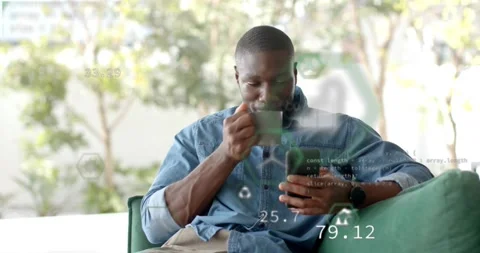 Man on green sofa tapping phone, sipping mug, checking sustainability via AR hex Video stock 321715141