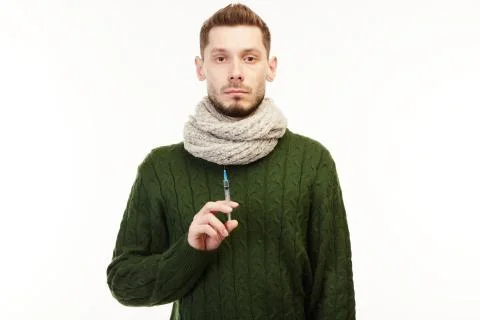 Man in a green sweater on the white background holds a syringe. Stock Photos