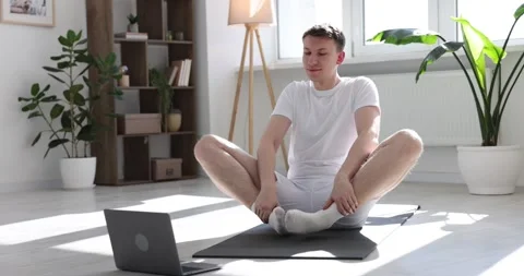 Man greeting his coach during online yoga class via laptop at home Stock Footage 310010893