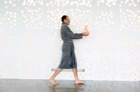 Man in grey bathrobe, walking, holding a vase, side view Stock Photos