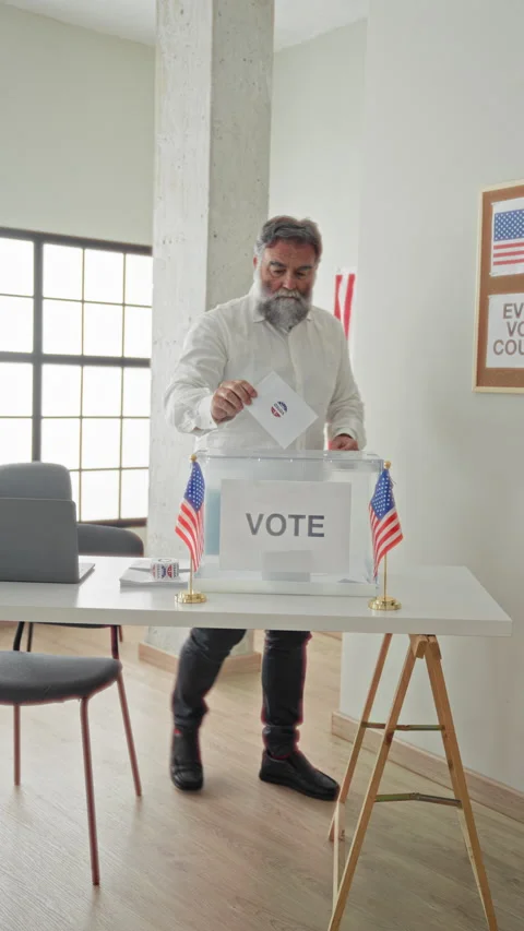 Man with grey beard inserts paper ballot into clear plastic ballot box on t.. Stock Footage 339200533