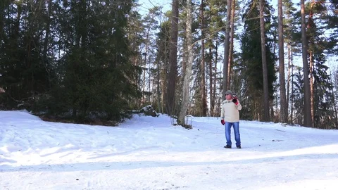 Man in grey hat and blue jeans walks in snow holding skis Stock Footage 108175560