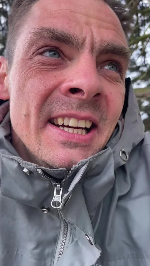 Man in grey jacket closeup talking outdoors near trees and sidewalk Видео 335355311