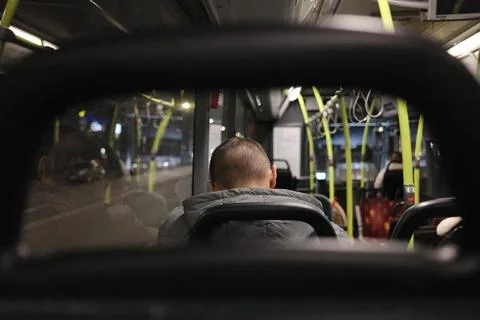 Man in grey jacket sits in a bus at night Stock Photos
