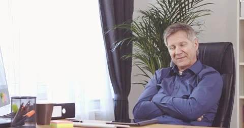 Man with grey is satisfied with work done at his desk 스톡 동영상 61135322