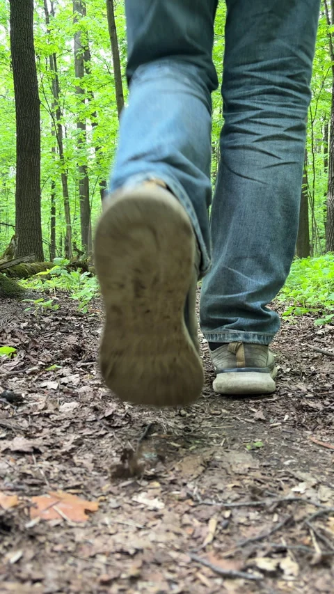 Man in grey worn outfit steps over the camera in a forest Stock Footage 310173371