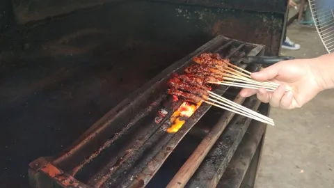 A man is grilling chicken satay Stock Footage 195281488