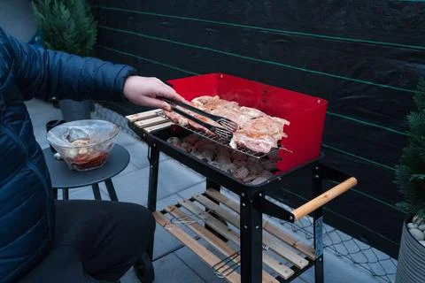 Man Grilling Marinated Meat on a Portable Barbecue in a Cozy Outdoor Setting. Stock Photos