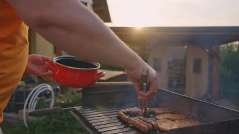 Man Grilling Meat on BBQ Backyard Cooking at Sunset Stock Footage 333580873