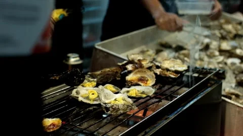 Man grilling oysters using torch with large flame Stock Footage 318709380