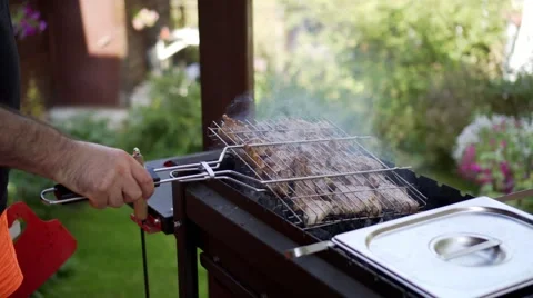 Man grilling pork meat on brazier, flipping pieces Stock Footage 68675390