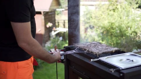 Man grilling pork meat on brazier, flipping pieces Stock Footage 68675440