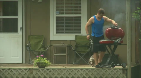 Man Grilling in the Rain 1 Stock Footage 52067284