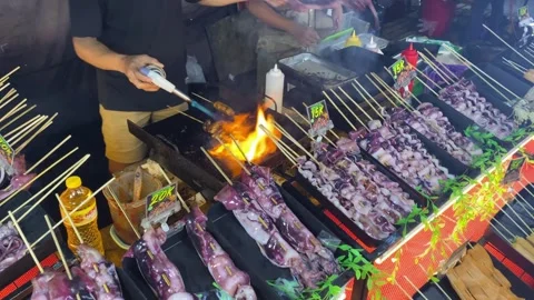 A man is grilling squid satay using kitchen blowtorch Stock Footage 347543631