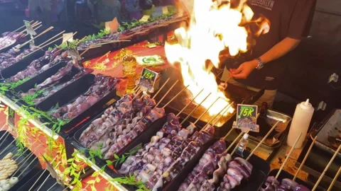 A man is grilling squid satay using kitchen blowtorch Stock Footage 347543633