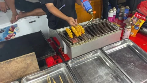 A man is grilling squid satay using kitchen blowtorch Stock Footage 347543649