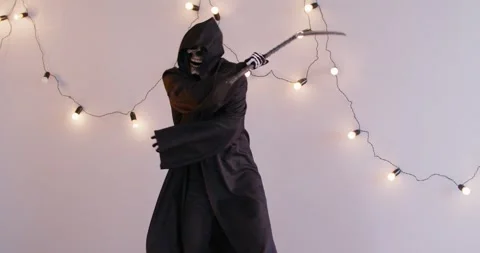 Man in grim reaper death costume dancing and waving his scythe during Halloween Stock Footage 314966623