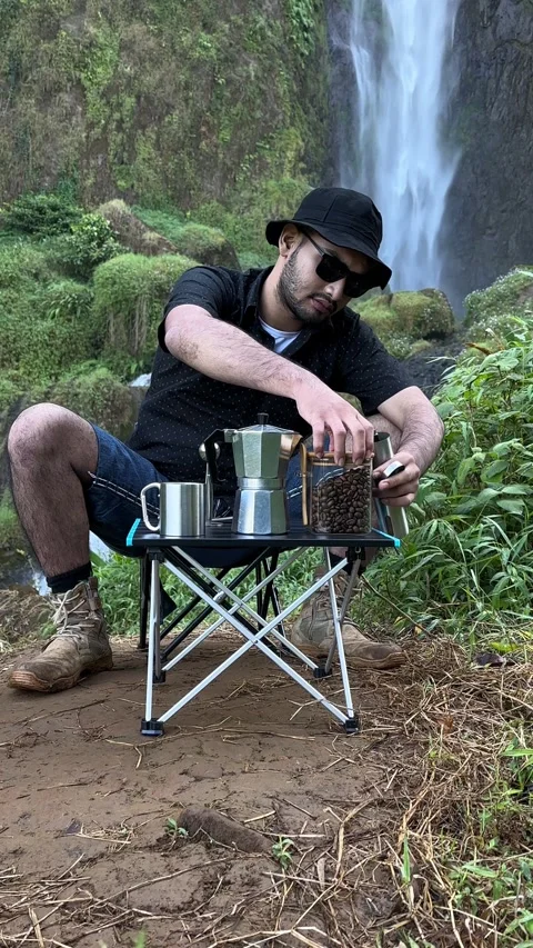 Man Grinding Coffee Beans, Making Coffee by Scenic Waterfall, Vertical Shot. Stock Footage 323907646