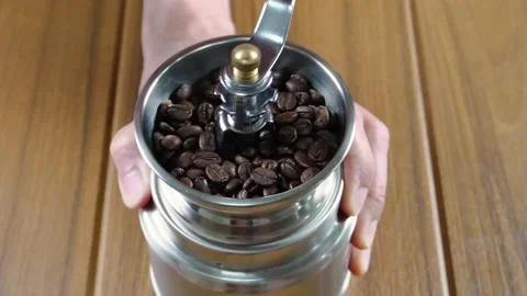 Man grinding coffee beans using a manual hand coffee grinder Stock Footage 197739341