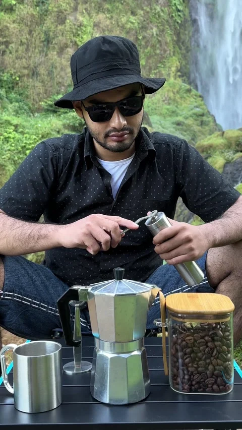 Man Grinding Coffee Beans by Waterfall in Forest, Vertical Medium Shot Stock Footage 323907703