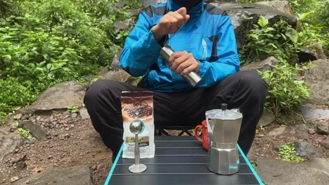 Man Grinding Fresh Coffee Beans in Forest, Outdoor Adventure, Medium Shot Stock Footage 324850394