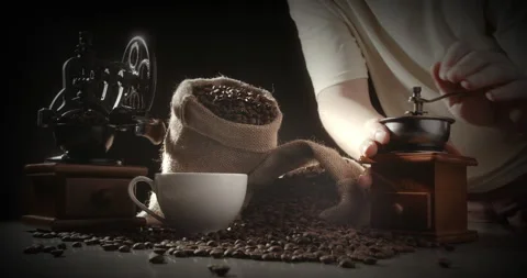 Man grinds coffee beans through manual coffee grinder. Hot cup and handful Stock Footage 222608455