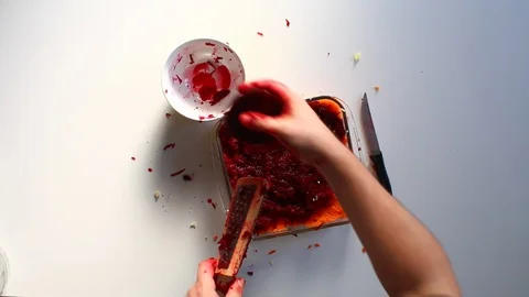 The man grinds the cooked beet onto a grater and distributes it evenly over the  Vídeo Stock 87648133