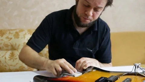 The man grinds the deck of the guitar with sandpaper. Day, indoors, real time, m Stock Footage 83561978