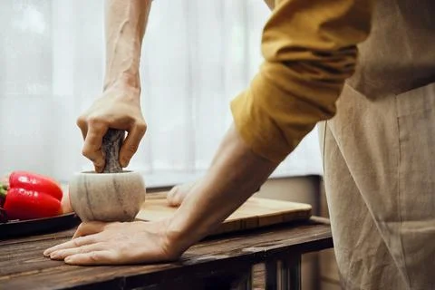 A man grinds pepper in a mortar using a pestle Stock-Fotos