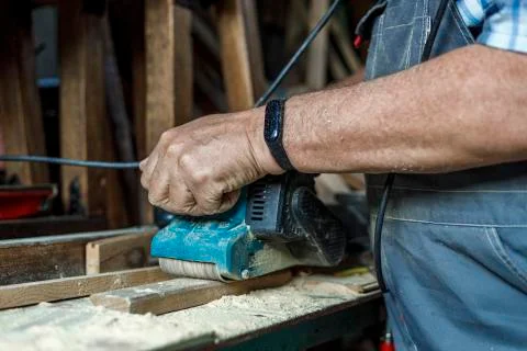 Man grinds the wood of angular grinding machine. Home carpentry workshop Stock Photos