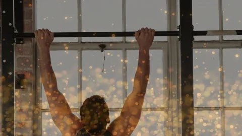 Man gripping pull-up bar and doing pullups for strength in gym, gold particles Stock Footage 330540599