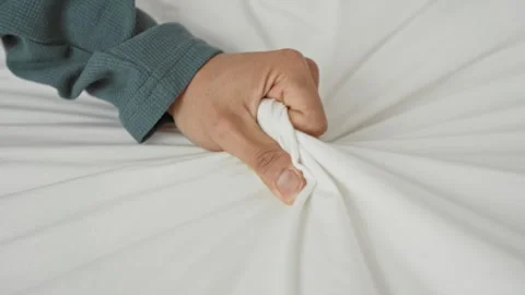 Man gripping white sheet with hand and clenched fingers, pulling bedding on.. Stock Footage 337431480