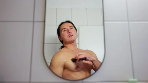 A man is grooming himself while closely observing his reflection in the bathroom Video stock 310335090