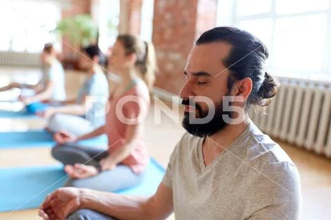 Man with group of people meditating at yoga studio Stock Photos