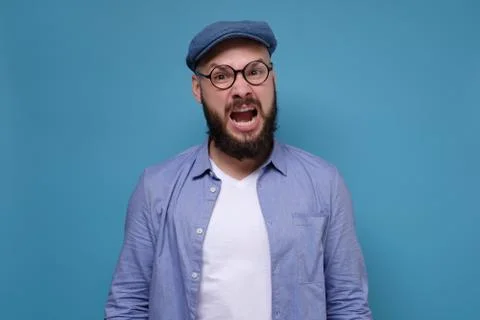 Man with grumpy grimace on his face, with mouth opened in shout 스톡 사진