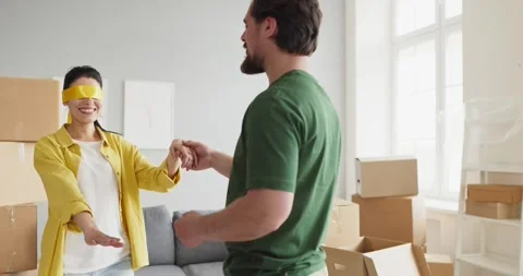 Man guiding blindfolded partner in new apartment on cheerful moving day together Stock Footage 341283191