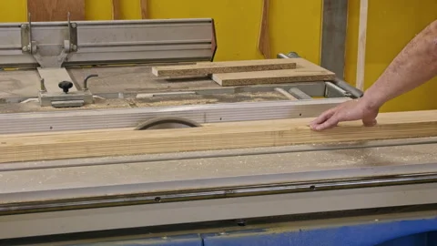 Man guiding wood through table saw Видео 337551584