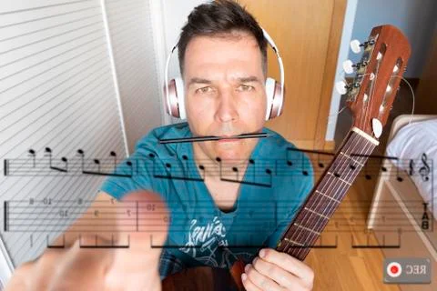 Man with a guitar looking at a computer screen learning music Stock Photos