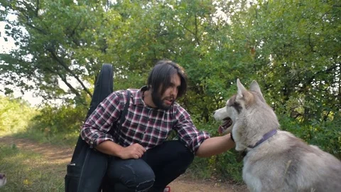 Man with guitar playing with two siberian husky dogs in forest Vidéo 84333011