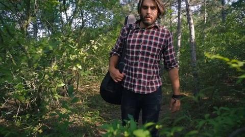 Man with guitar walking in forest Video stock 84380023