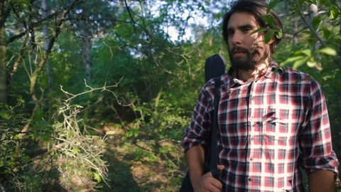 Man with guitar walking in forest Stock Footage 84380586