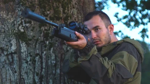 Man with a gun on the hunt behind a tree 4k Video stock 80320619