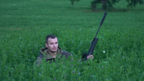 Man with a gun sitting in the tall grass 스톡 동영상 80312592